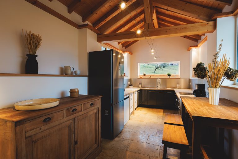 Cuisine ouverte et salon lumineux du Gîte Au Verger, avec poutres apparentes et espace convivial idéal pour des moments en famille.